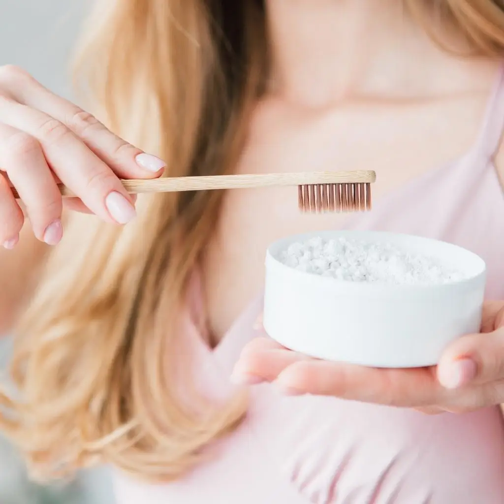 A person prepares to use a bamboo toothbrush with natural toothpaste, demonstrating an individual's commitment to eco-friendly oral care.